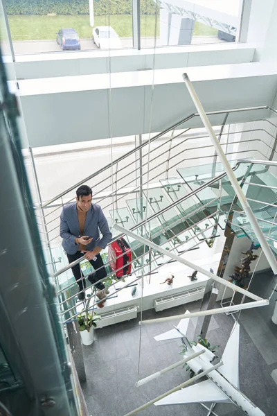 Hombre con documentos de viaje y teléfono apoyado en la barandilla de la escalera — Foto de Stock