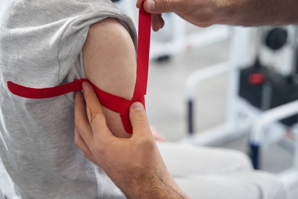Medic colocar tecido auto adesivo bandagem no braço — Fotografia de Stock