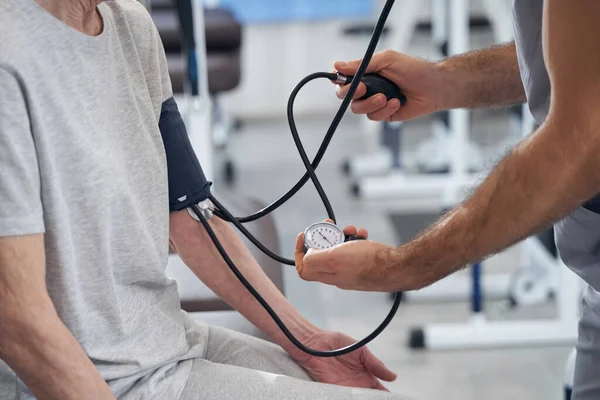 Měřič krevního tlaku používaný lékařem u stárnoucí osoby — Stock fotografie