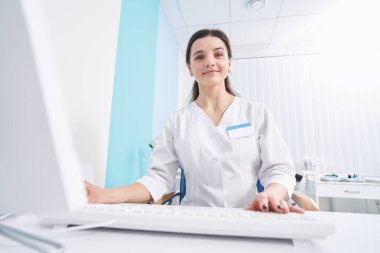 Ofisinde oturmuş gülümseyen mutlu genç doktor.