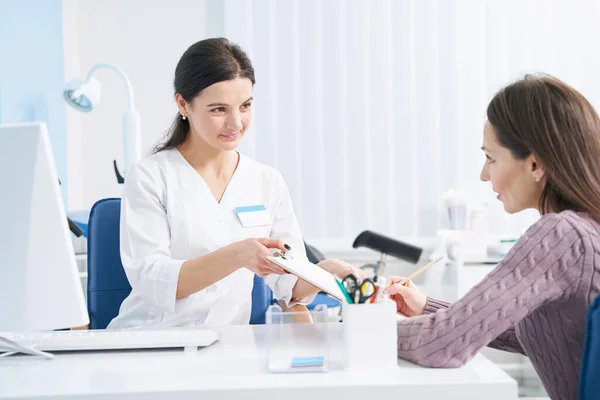 Female patient affixing her signature to document in doctor office — Stock Photo, Image