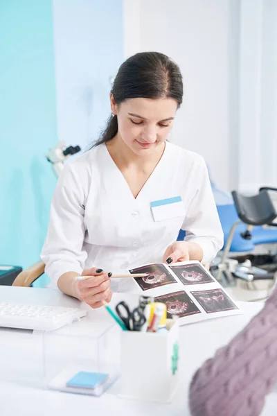 Fokuserad diagnostiker tittar på ultraljudsbilder i hennes händer — Stockfoto