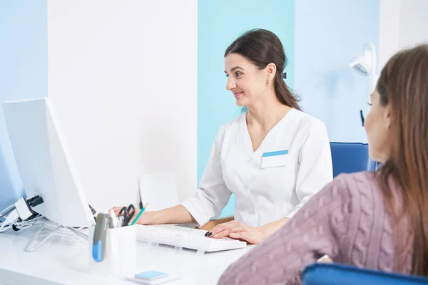 Cheerful young woman physician receiving her patient — Stock Photo, Image