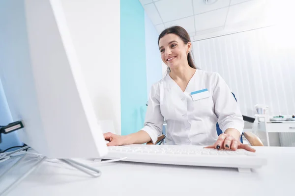 Leende nöjd fokuserad kvinnlig läkare arbetar på sitt kontor — Stockfoto