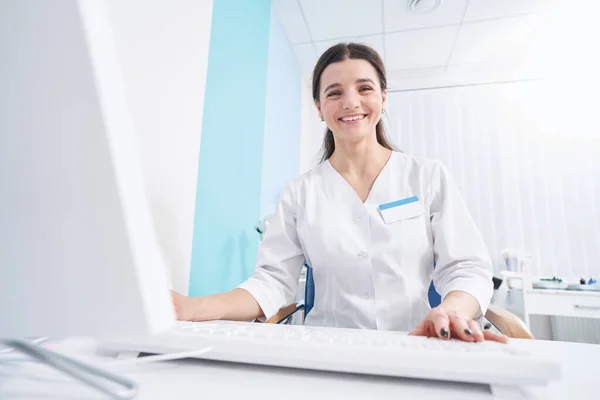 Весела жінка-лікар сидить на робочому місці — стокове фото