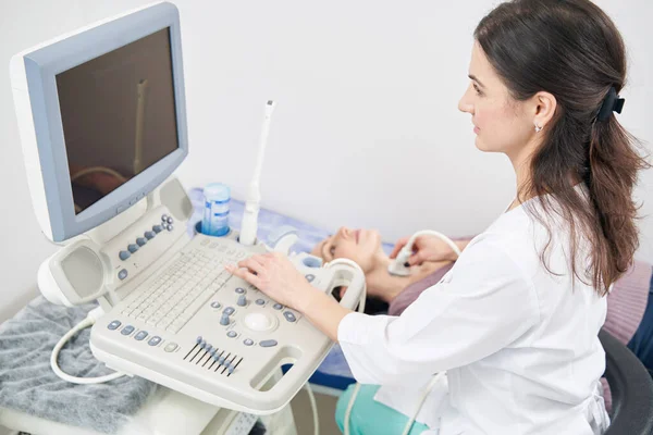 Soustředěný diagnostik vyšetřující pacienta na ultrazvukovém přístroji — Stock fotografie