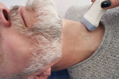 Tiroid ultrason muayenesi yapan Kafkasyalı profesyonel bir teşhis uzmanı.