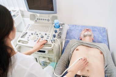 Yetişkin beyaz bir adam karın ultrasonu yaptırıyor.