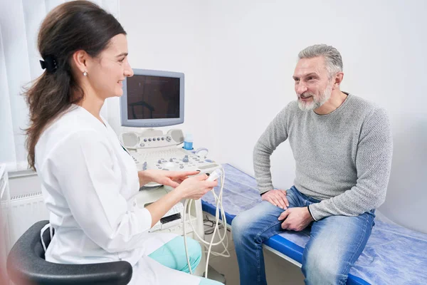 Sonriente médico amable hablando con el paciente masculino antes de la ecografía — Foto de Stock