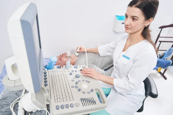 Koncentrovaný diagnostik provádějící ultrazvuk štítné žlázy — Stock fotografie