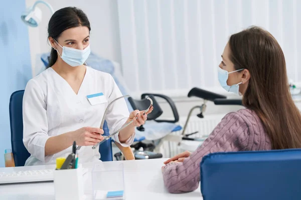 Žena gynekoložka demonstrující lékařské nástroje pro ženy — Stock fotografie