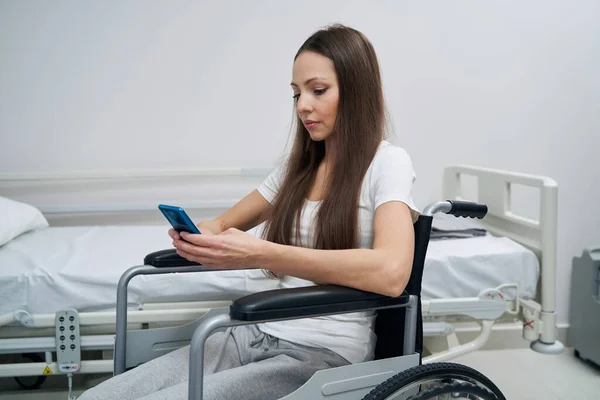 Mujer discapacitada concentrada leyendo mensaje de texto en su teléfono celular —  Fotos de Stock