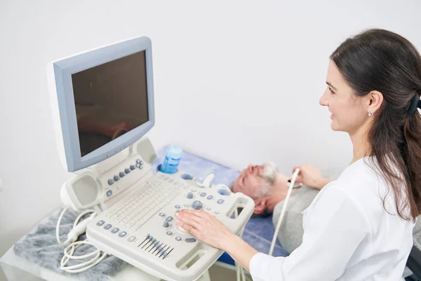 Smiling experienced female diagnostician performing thyroid ultrasound — Stock Photo, Image