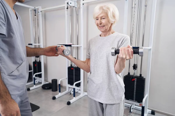 Seniorin trainiert mit Kurzhanteln in jeder Hand — Stockfoto