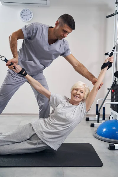 Happy aging woman pulling two cables during sport exercise — Stock Photo, Image