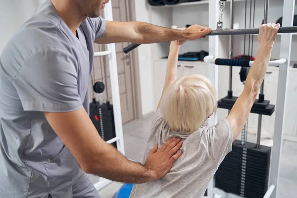 Manueller Therapeut korrigiert alte weibliche Körperhaltung während des Trainings — Stockfoto