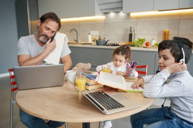 Baba, oğul ve kız işlerini mutfakta yapıyorlar.