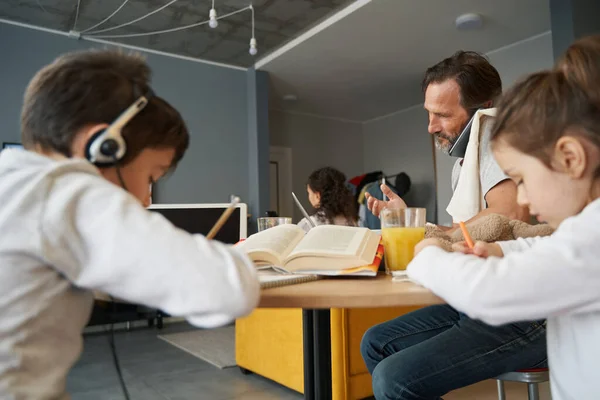 Barn målar och gör läxor medan far har telefonsamtal — Stockfoto