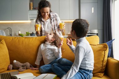 Neşeli kadın çocuklara iki bardak meyve suyu getiriyor.
