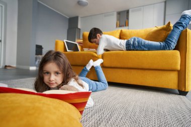 Kardeşi okumadan önce kitaplarını yere sermiş bir kız.