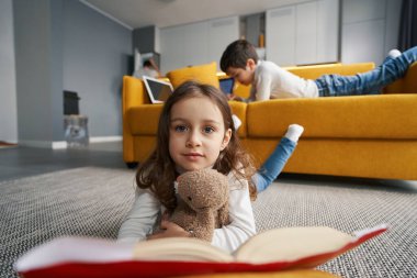 Oyuncak ayılı kız yerden kameraya bakıyor.