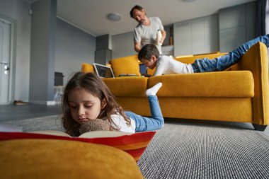 Çocuk yerde kitaptan hikayeler okuyor.