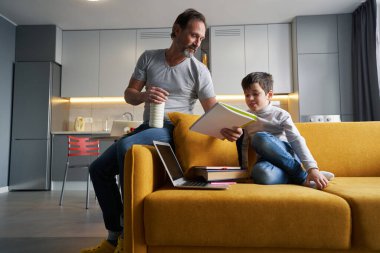 Oğlunun okul ödevindeki hatalarını açıklayan adam.