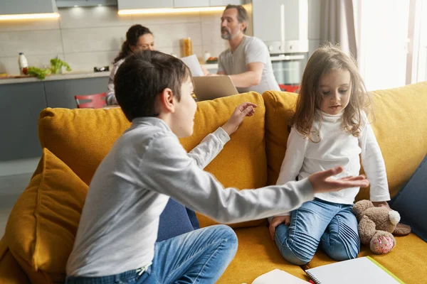 Chico diciendo algo a su hermana pequeña en el sofá — Foto de Stock