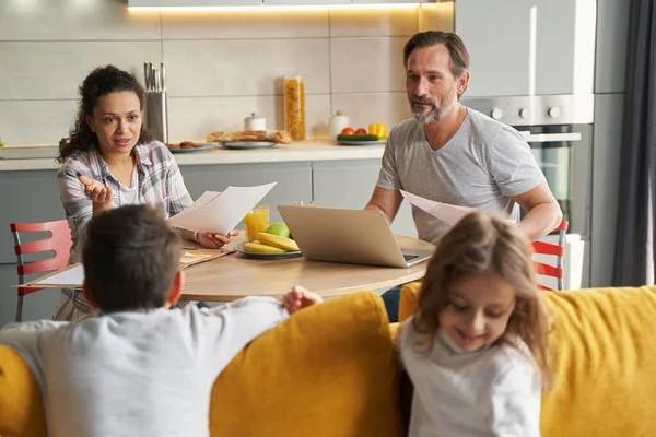 Mother addressing her children on couch during work with documents — Stock Photo, Image