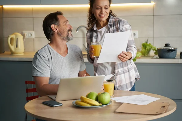 Pleased wife staring at document of her working husband — Stock Photo, Image