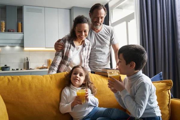 Orgulhosos pais olhando para seus filhos com suco — Fotografia de Stock