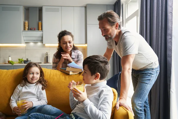 Padres admirando a sus hijos con jugo en el sofá — Foto de Stock