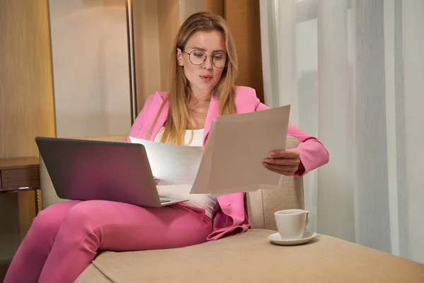 Erfolgreiche Frau im rosafarbenen Anzug führt Geschäft vom Hotelzimmer aus — Stockfoto
