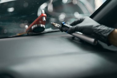 Ön cam onarım matkabıyla eldivenli el torpido gözünde yatıyor.