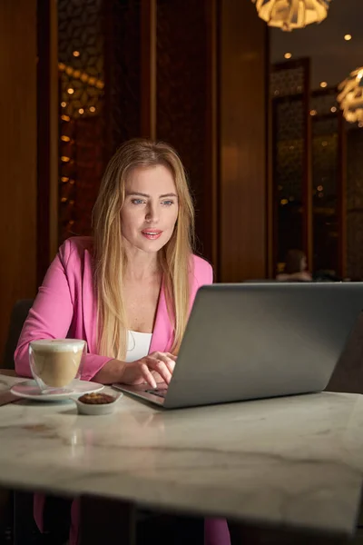 Окаменелая молодая женщина работает на ноутбуке в кафе — стоковое фото