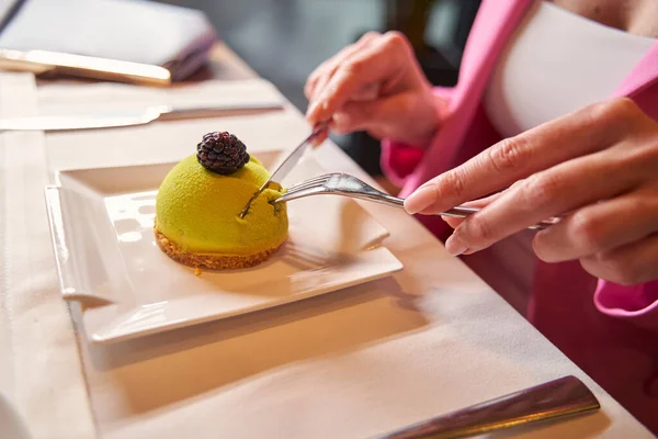 Persoon aan de cafe tafel snijden van een stuk heerlijke groene dessert — Stockfoto