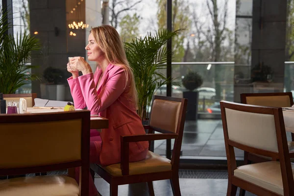 Senhora loira agradável com xícara de café lounging no café — Fotografia de Stock
