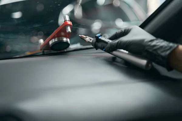 Gloved hand with windscreen repair drill lying on dashboard cover — Stock Photo, Image