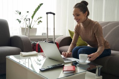 Otel odasında taşınabilir bilgisayarda çalışan bir kadın.