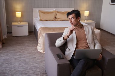 İçerde oturan taşınabilir bilgisayarlı sakin bir adam.