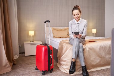 Neşeli turist otel odasında mesaj okuyor.