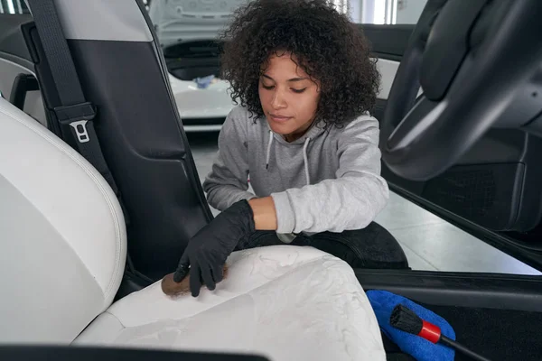 Skilled car shop worker brushing leather vehicle upholstery — Stock Photo, Image