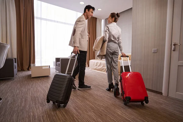 Homem satisfeito e seu companheiro com bagagem no quarto de hotel — Fotografia de Stock