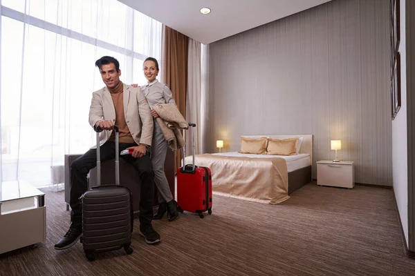 Feliz pareja de turistas con equipaje en la habitación del hotel — Foto de Stock