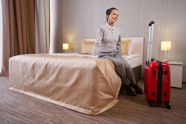 Jovencita alegre sentada en la habitación del hotel — Foto de Stock