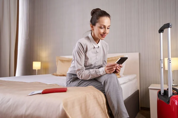 Γυναίκα ανάγνωση μήνυμα κειμένου στο κινητό τηλέφωνο στο δωμάτιο του ξενοδοχείου — Φωτογραφία Αρχείου