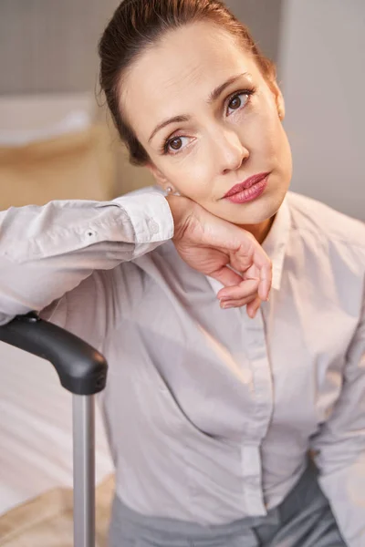 Nachdenkliche Frau mit Gepäck sitzt allein im Hotelzimmer — Stockfoto