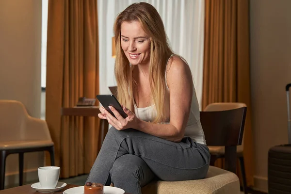 Donna nella suite dell'hotel cliccando sul suo smartphone — Foto Stock
