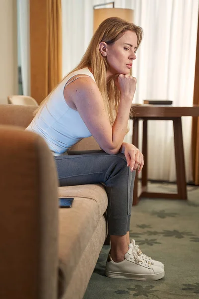 Mulher profundamente em pensamentos sentados no sofá no hotel — Fotografia de Stock