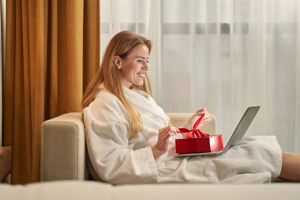 楽しいです女性でローブオープニングプレゼント上のラップトップ — ストック写真